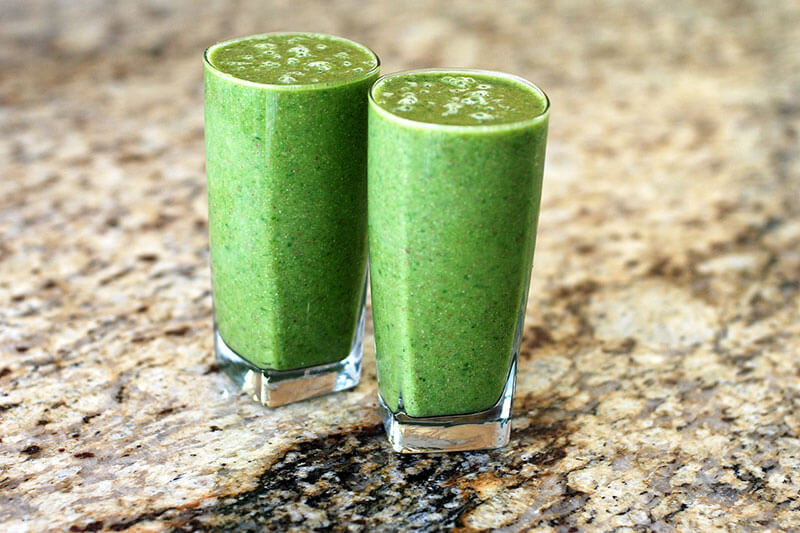 Picture of two glasses full of a green smoothie