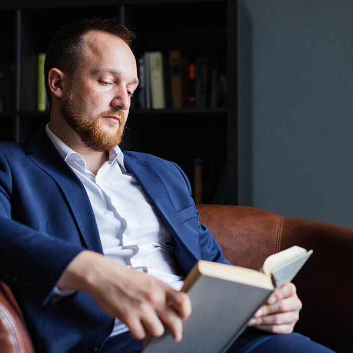 Middle-aged man sitting in home library reading book - Radiant Health SF Men's Health