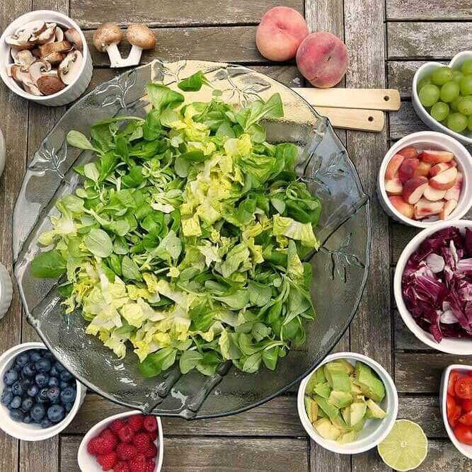 Big salad bowl with different healthy food options around it